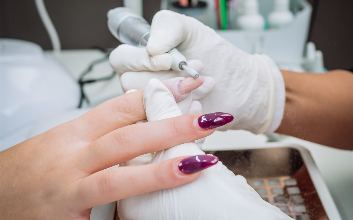 Nail technician using an electric file to remove acrylic gel