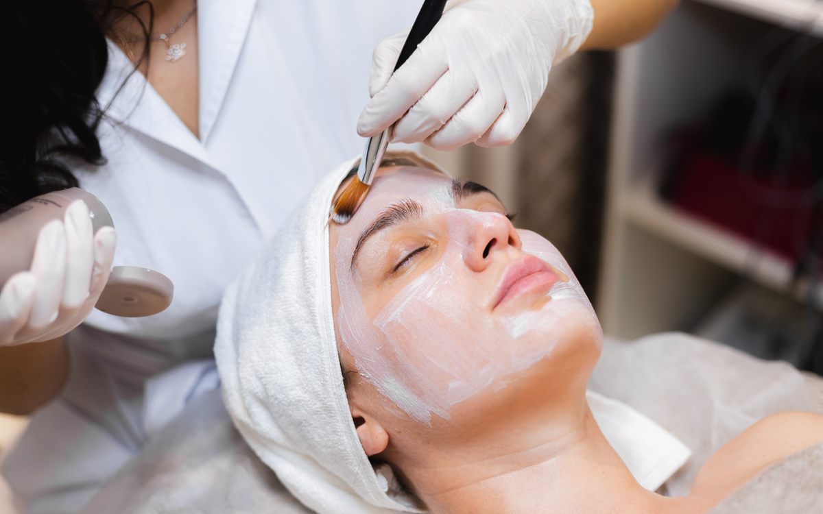 Beauty therapist applying a facial mask to a client with a brush