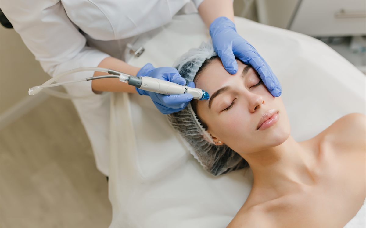 Cosmetologist performing a hydrafacial machine treatment on a client